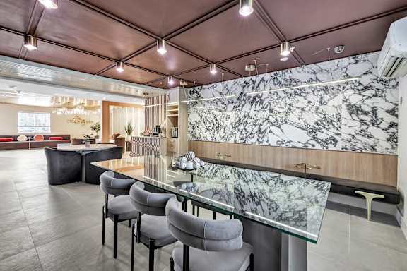 a dining area with a glass table and chairs and a marble wall at The Meriden, Meriden, 06450