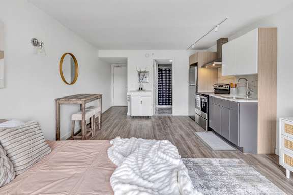 a living room with a bed and a kitchen with a sink