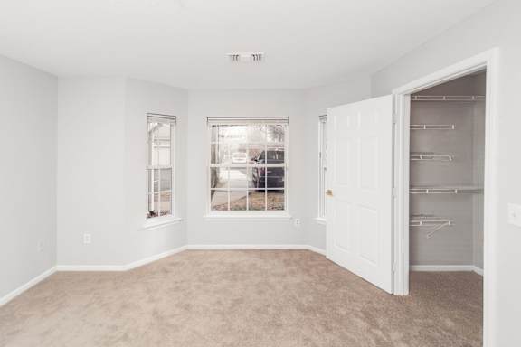 A room with a white door and a window with a view of a street.