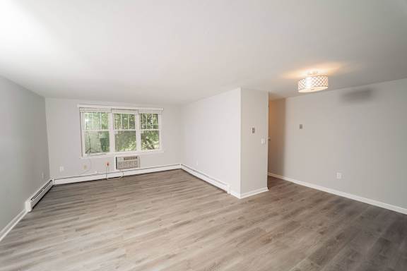 a living room with wood floors and white walls and a window  at Enclave West Hartford / Parc West, West Hartford