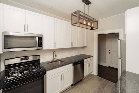 a kitchen with white cabinets and a black stove and a microwave
