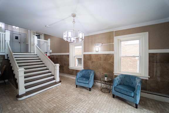 a living room with two blue chairs and a staircase