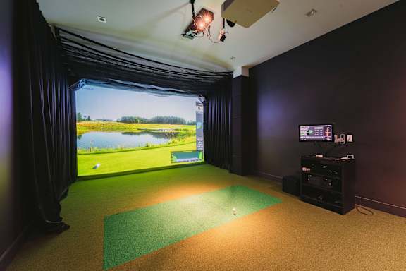 a room with a view of a golf course and a projector screen on the wall at Up House, Farmington, CT