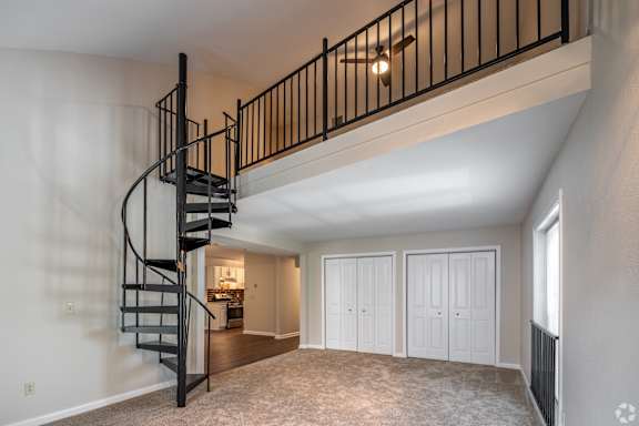 A spacious room with a spiral staircase leading to the upper floor.