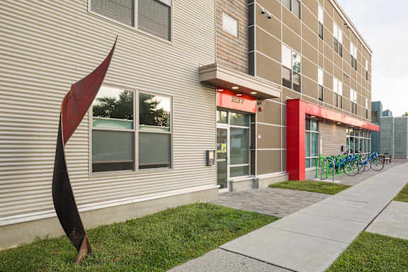 A modern building with a red awning and a sculpture in front of it.