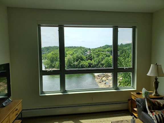 A room with a large window overlooking a river and trees.