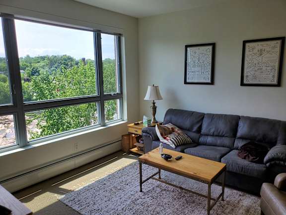 A living room with a black couch and a large window.