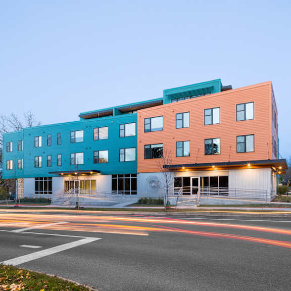 A modern multi-story building with a mix of blue and orange panels.