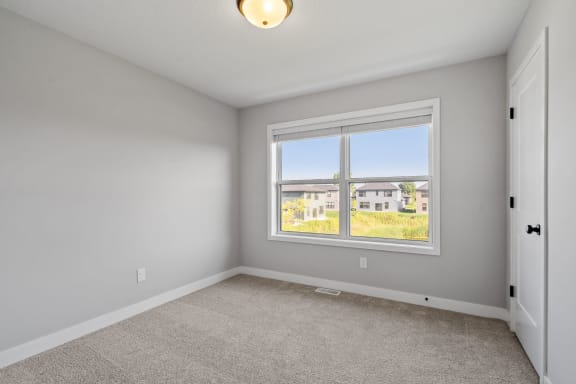 an empty bedroom with a large window and carpeting