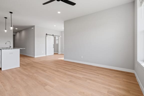 a living room and kitchen with wood flooring and a ceiling fan