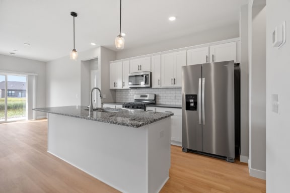 a kitchen with a large island and a stainless steel refrigerator