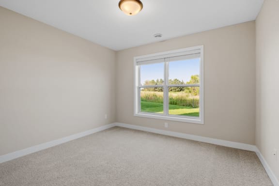an empty bedroom with a large window and carpeting