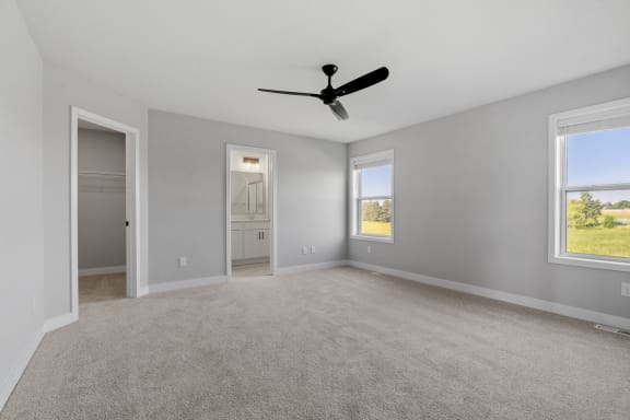 an empty living room with a ceiling fan and a door to a hallway