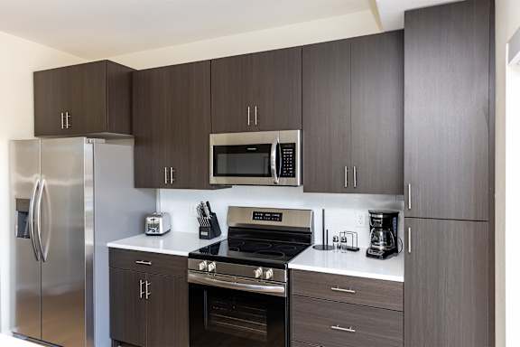 A modern kitchen with dark brown cabinets and stainless steel appliances.