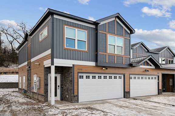 A modern house with a grey and brown exterior and a white garage door.