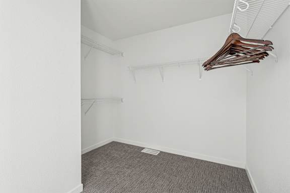 A room with a grey carpet and clothes hanging on a rack.
