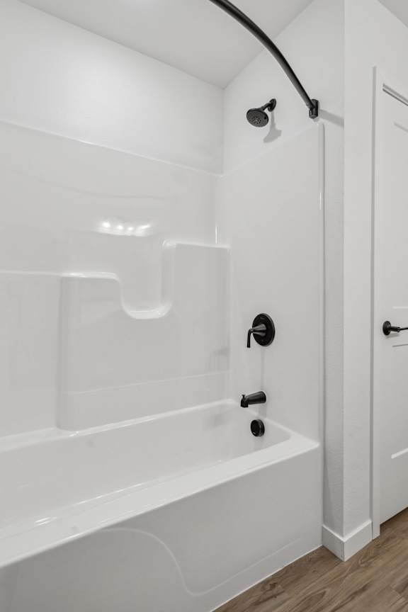 A white bathroom with a tub and a shower head.