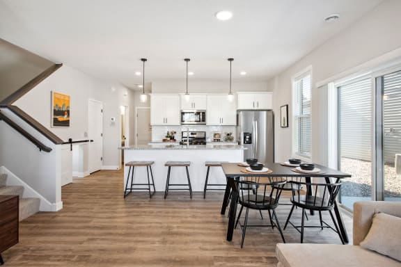 a dining area with a table and chairs and a kitchen in the background