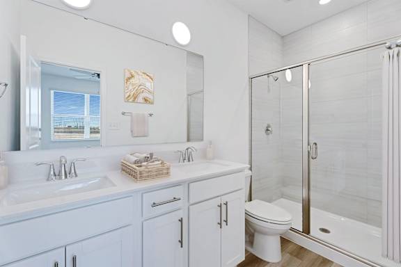 A white bathroom with a toilet, sink, and shower.