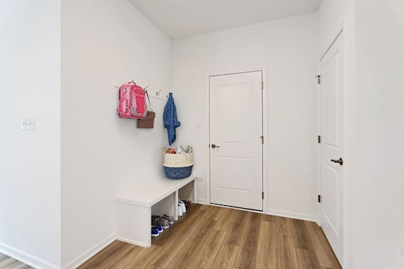 A room with a bench and a coat hanging on the wall.