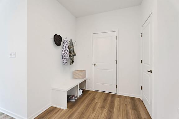 A white hallway with a bench and a coat rack.