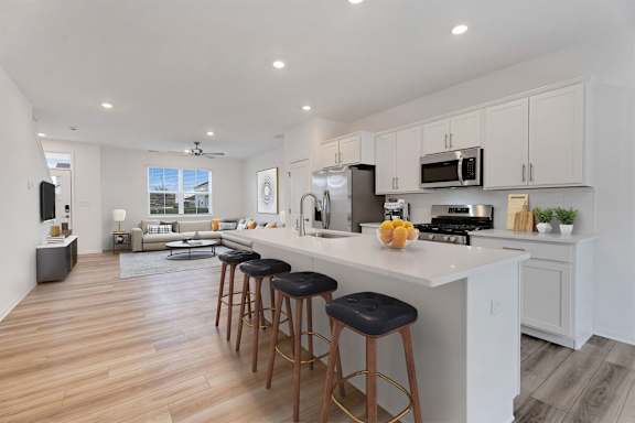 A kitchen with a white countertop and bar stools.