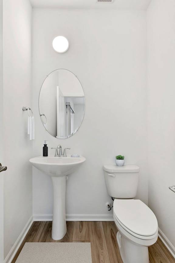 A white bathroom with a sink, toilet and mirror.