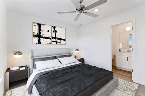 A bedroom with a bed, nightstands, and a ceiling fan.
