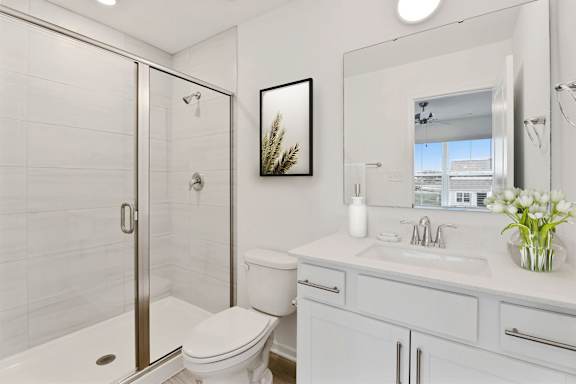 A white bathroom with a toilet, sink, and mirror.