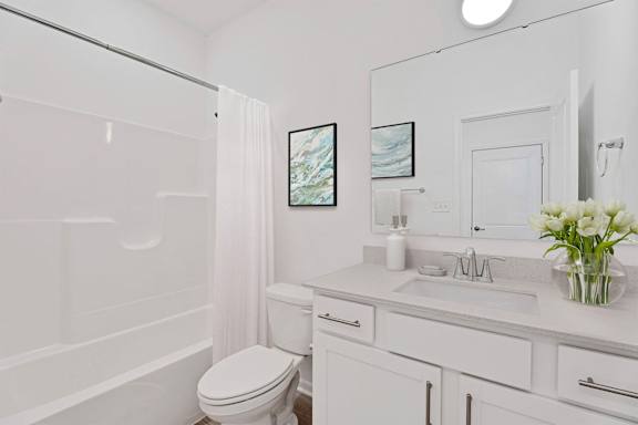 A white bathroom with a toilet, sink, and a large mirror.
