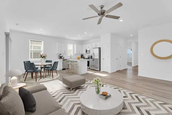 A modern living room with a grey sofa, a round coffee table, and a ceiling fan.