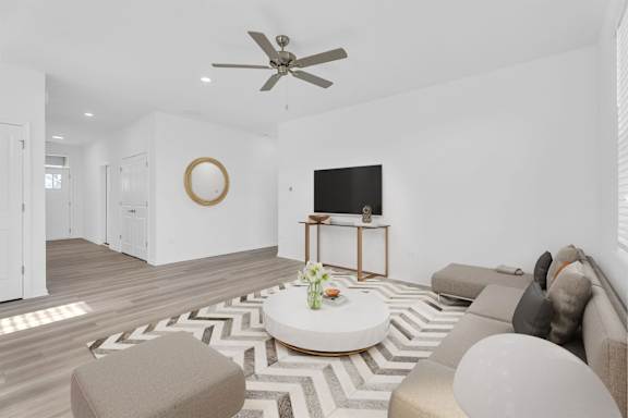 A living room with a white couch, a coffee table, and a ceiling fan.