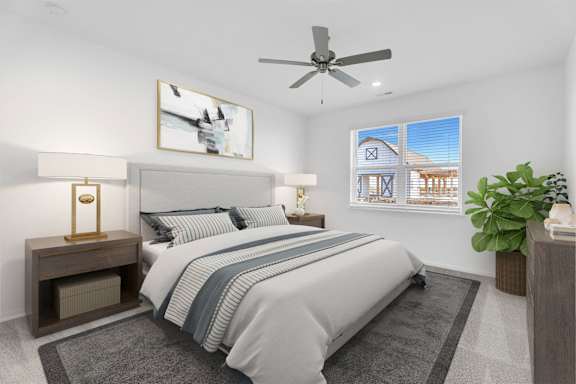A bedroom with a bed, a ceiling fan, and a painting on the wall.