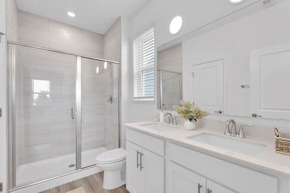 A white bathroom with a walk-in shower and double sinks.