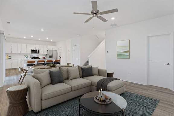 A living room with a beige couch, a coffee table, and a ceiling fan.