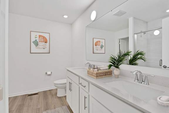 A white bathroom with a toilet, sink, and mirror.
