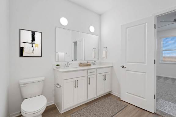 A bathroom with a toilet, sink, and mirror.