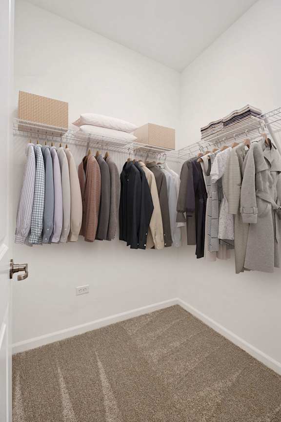A white closet with clothes hanging on a rack.