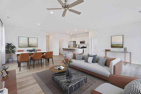 A modern living room with a grey sofa, a coffee table, and a dining table with chairs.