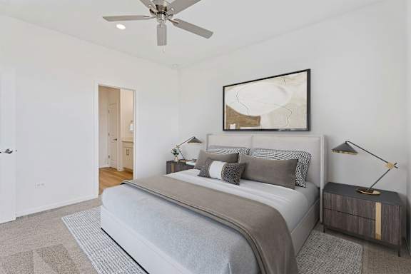 A bedroom with a large bed and a ceiling fan.