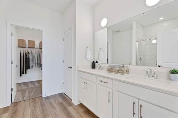 A bathroom with white cabinets and a large mirror.