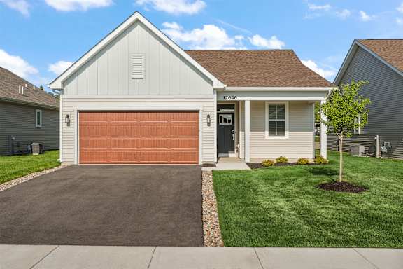 A house with a brown garage door and a white house number.