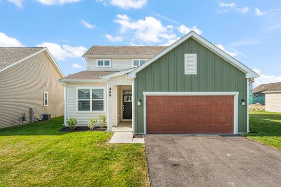 A house with a green garage door and a brown driveway.