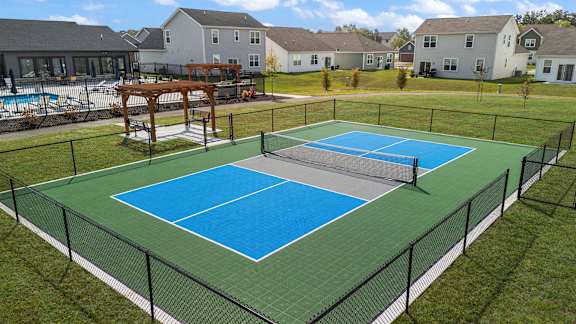 A tennis court with a blue surface and a black fence.