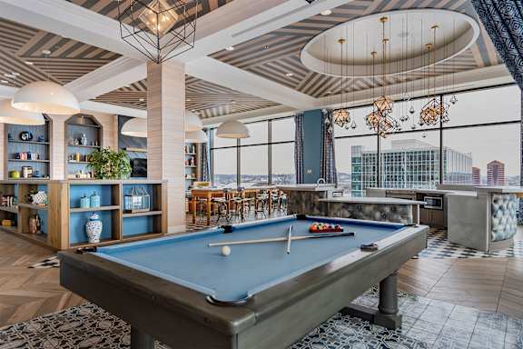 A pool table is in the middle of a room with a view of the city.