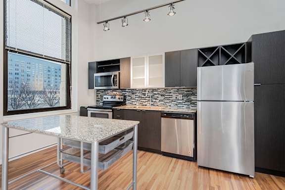 A modern kitchen with a granite countertop and stainless steel appliances.