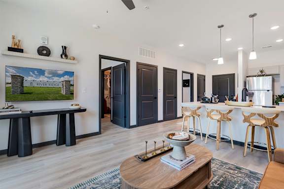 A modern living room with a wooden coffee table and a painting of a river ridge on the wall.
