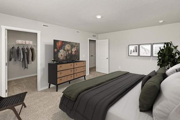 A bedroom with a bed, dresser, and a wall with pictures.