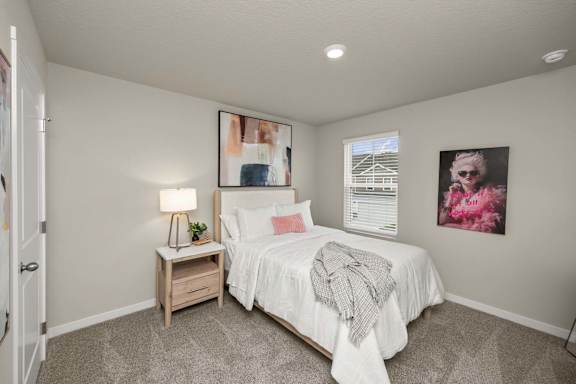 A bedroom with a bed, nightstand, and two pictures on the wall.