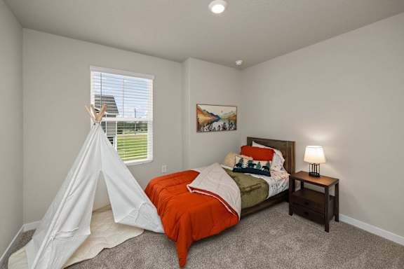 A bedroom with a bed, a teepee, and a painting on the wall.